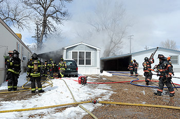 Berthoud Fire Protection District firefighters and Loveland Fire Rescue Authority firefighters work a mobile home on fire 205 Second Street, lot 6, in Berthoud on Friday, March, 25, 2016. (Photo by Jenny Sparks/Loveland Reporter-Herald)